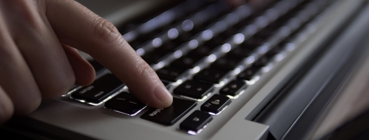 Woman's finger pressing delete button on laptop